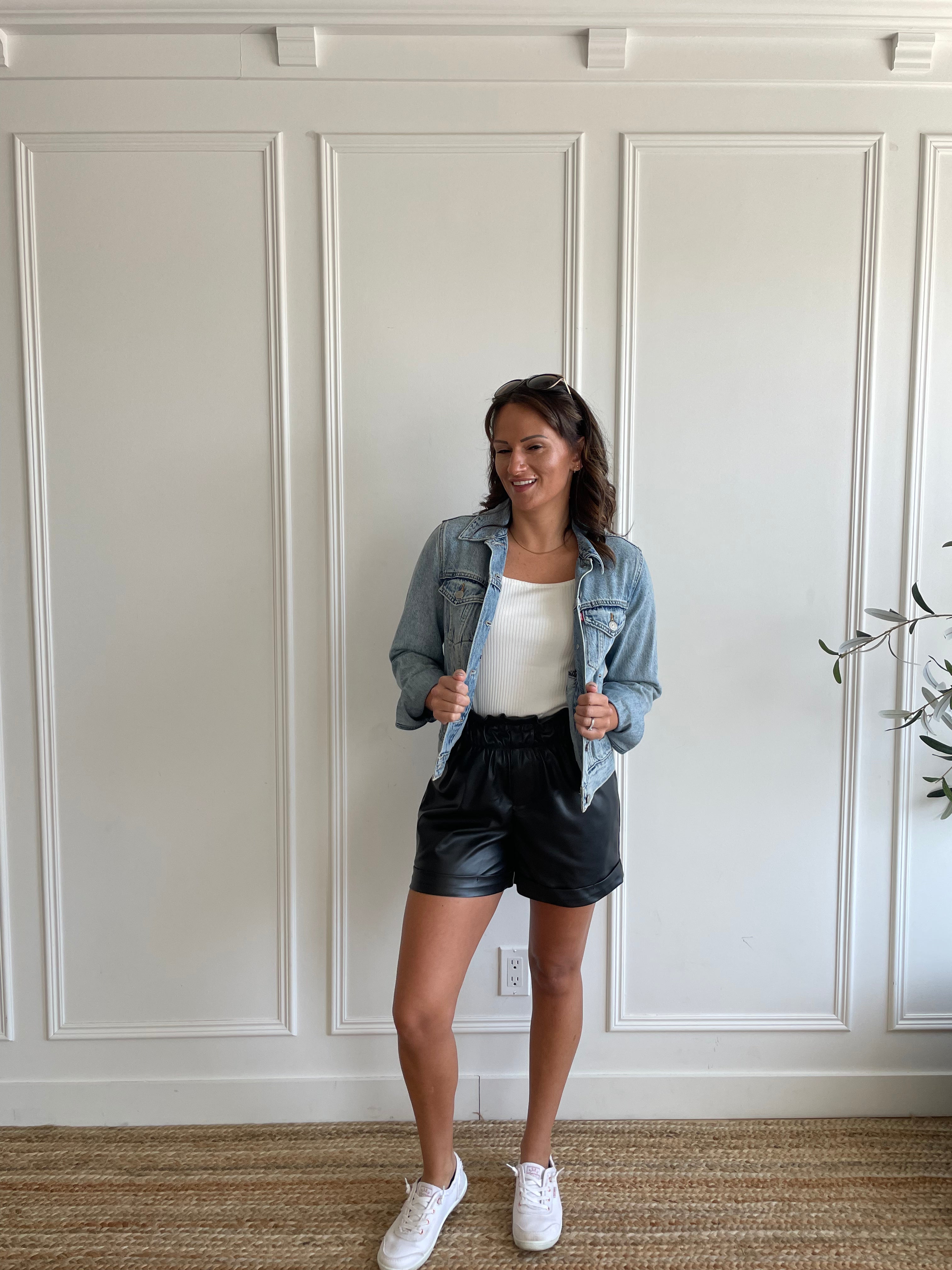 woman wearing square neck tank top and vegan leather paper bag shorts and denim jacket