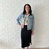 woman wearing jean jacket, graphic tee and black ribbed midi skirt with white sneakers