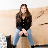 woman wearing black cardigan with jeans sitting down