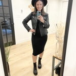 woman wearing black tank dress, leather jacket and black hat standing in mirror