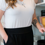 close up photo of woman wearing a white vneck tshirt and black wide leg pants. close up photo of waistband