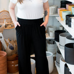 woman wearing a white vneck tshirt and black wide leg pants