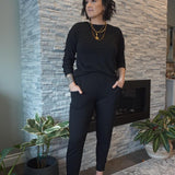 Model wearing black bamboo tapered joggers and black crewneck sweatshirt standing in front of fireplace