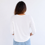 Person wearing a white shirt and light blue jeans against a white background