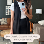 Woman taking a mirror selfie wearing a white t-shirt, black vest, and black skirt in a living room. Made in canada