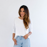 Woman wearing a white top and light blue jeans against a white background
