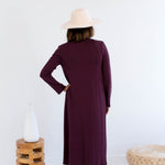 Woman wearing a long burgundy cardigan made in canada with a white background