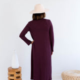 Woman wearing a long burgundy cardigan made in canada with a white background
