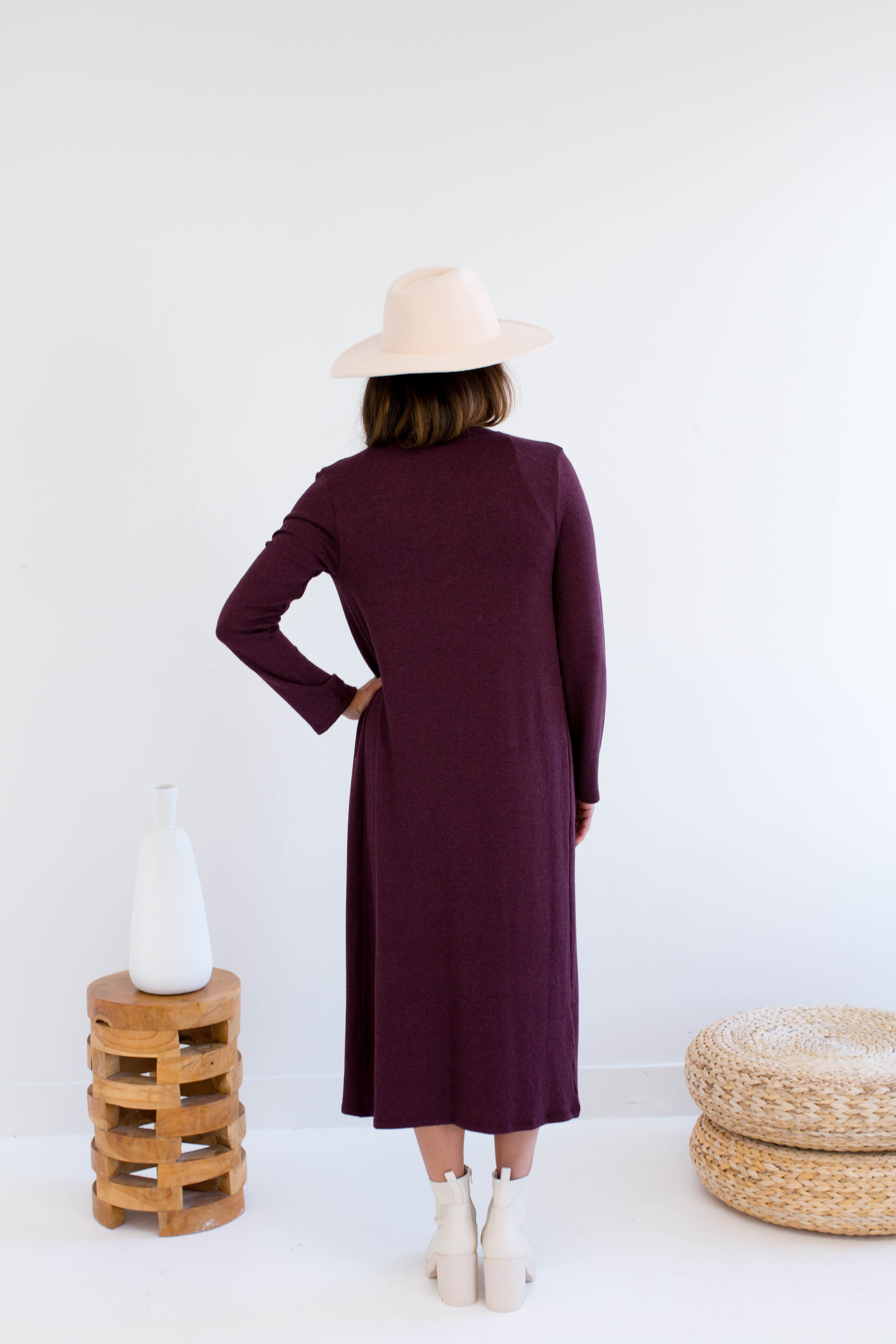 Woman wearing a long burgundy cardigan made in canada with a white background