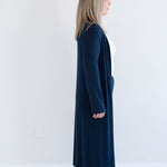 Person wearing a long navy blue cardigan against a white background