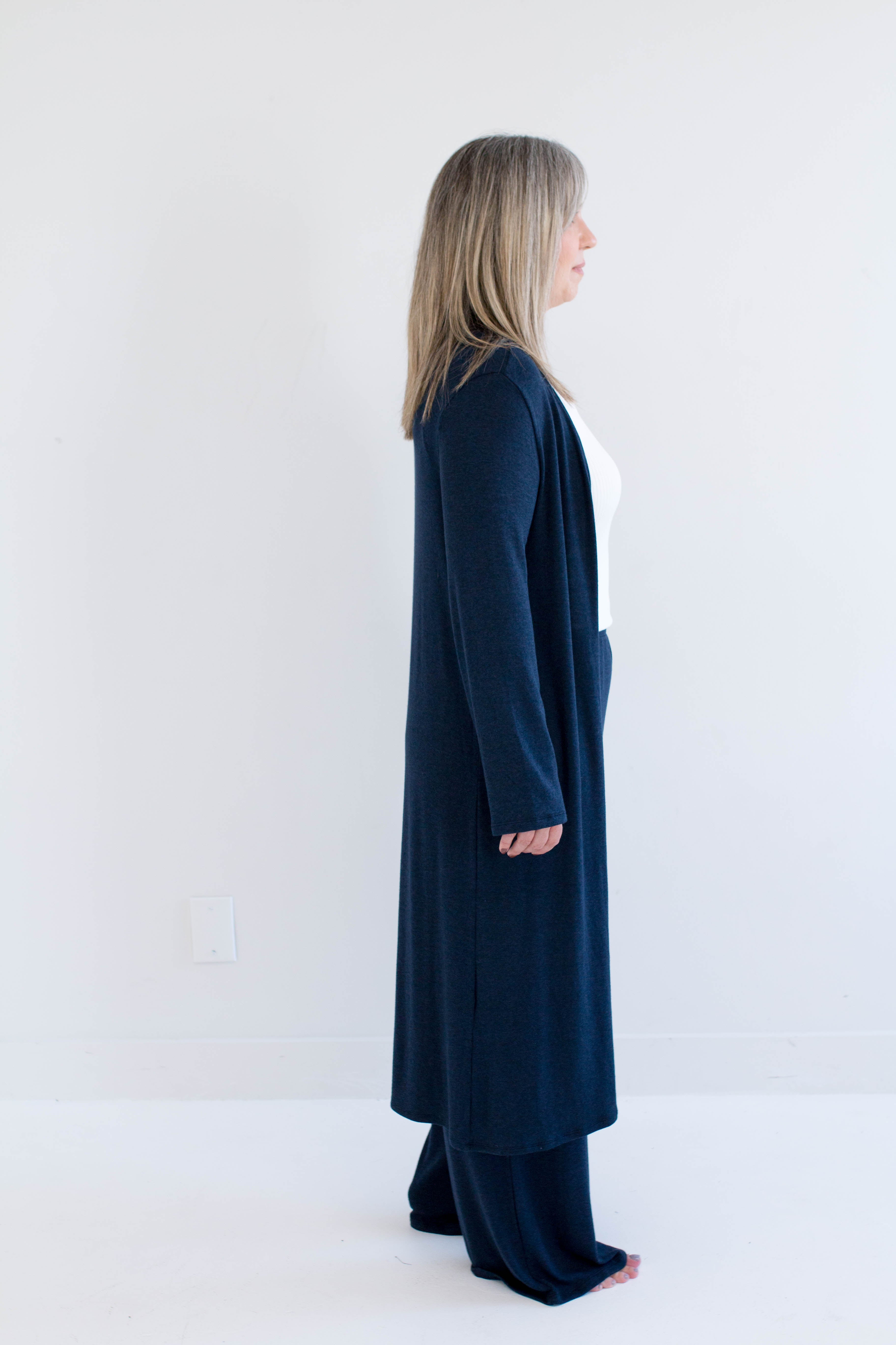 Person wearing a long navy blue cardigan against a white background