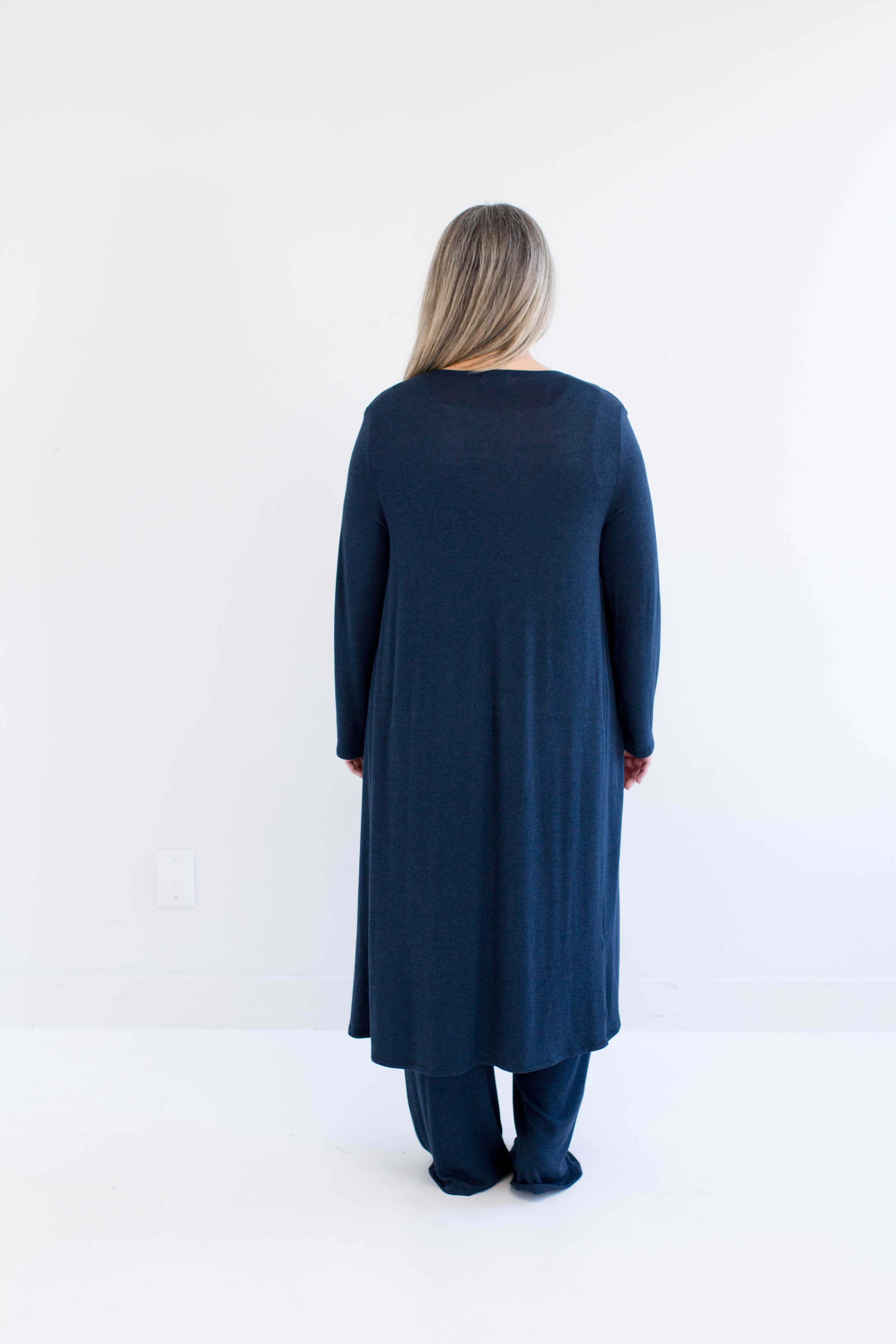 Woman wearing a long navy cardigan made in canada on a white background
