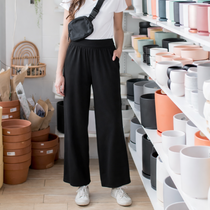 Woman standing in a pottery store with shelves of ceramic items wearing black wide leg bamboo pants made in canada