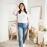 woman wearing long pink cardigan and white v-neck t-shirt and jeans