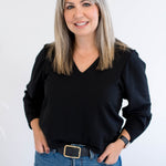 Woman wearing a black v-neck sweater and blue jeans against a white background. Made in Canada clothing.