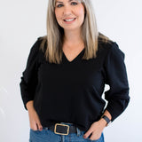 Woman wearing a black v-neck sweater and blue jeans against a white background. Made in Canada clothing.