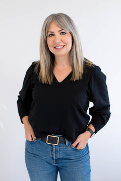 Woman wearing a black v-neck sweater and blue jeans against a white background. Made in Canada clothing.