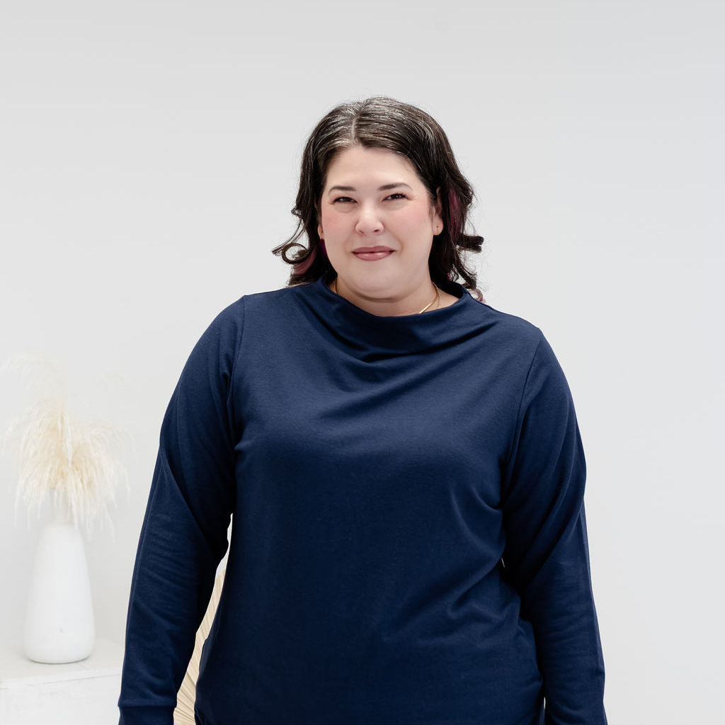 A woman modeling a matching navy blue long-sleeve top and pants set against a clean white studio background.