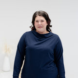 A woman modeling a matching navy blue long-sleeve top and pants set against a clean white studio background.