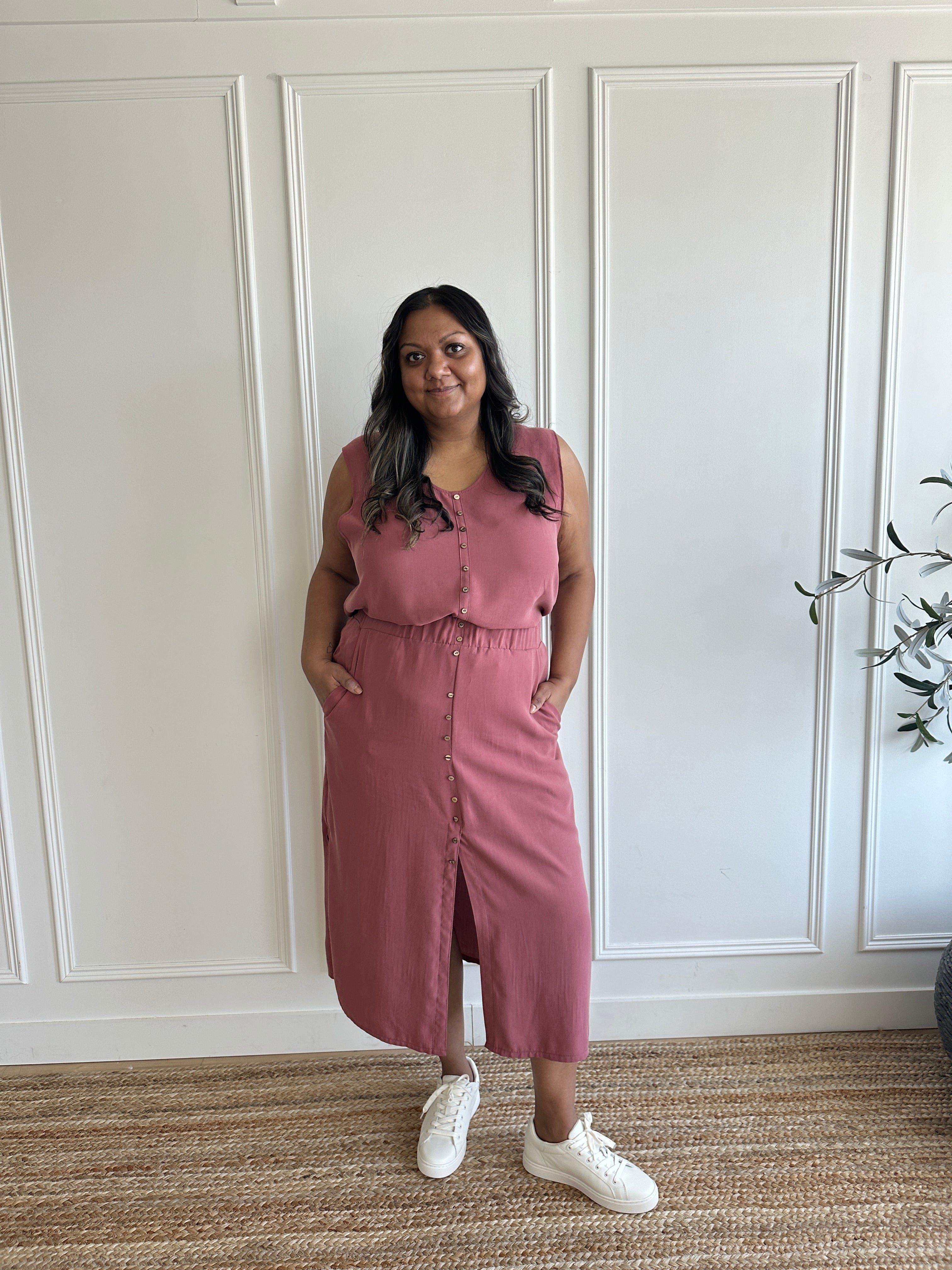 pink loose fitting tank top with brown buttons and pink loose fitting midi skirt with side slits with brown buttons on model standing wearing white sneakers