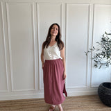 white loose fitting women's tank top with brown buttons and pink flowy midi skirt with side slits 