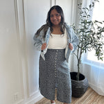 Indian woman wearing a denim jacket, white square neck tank top and black and white floral print midi skirt with buttons and side slits