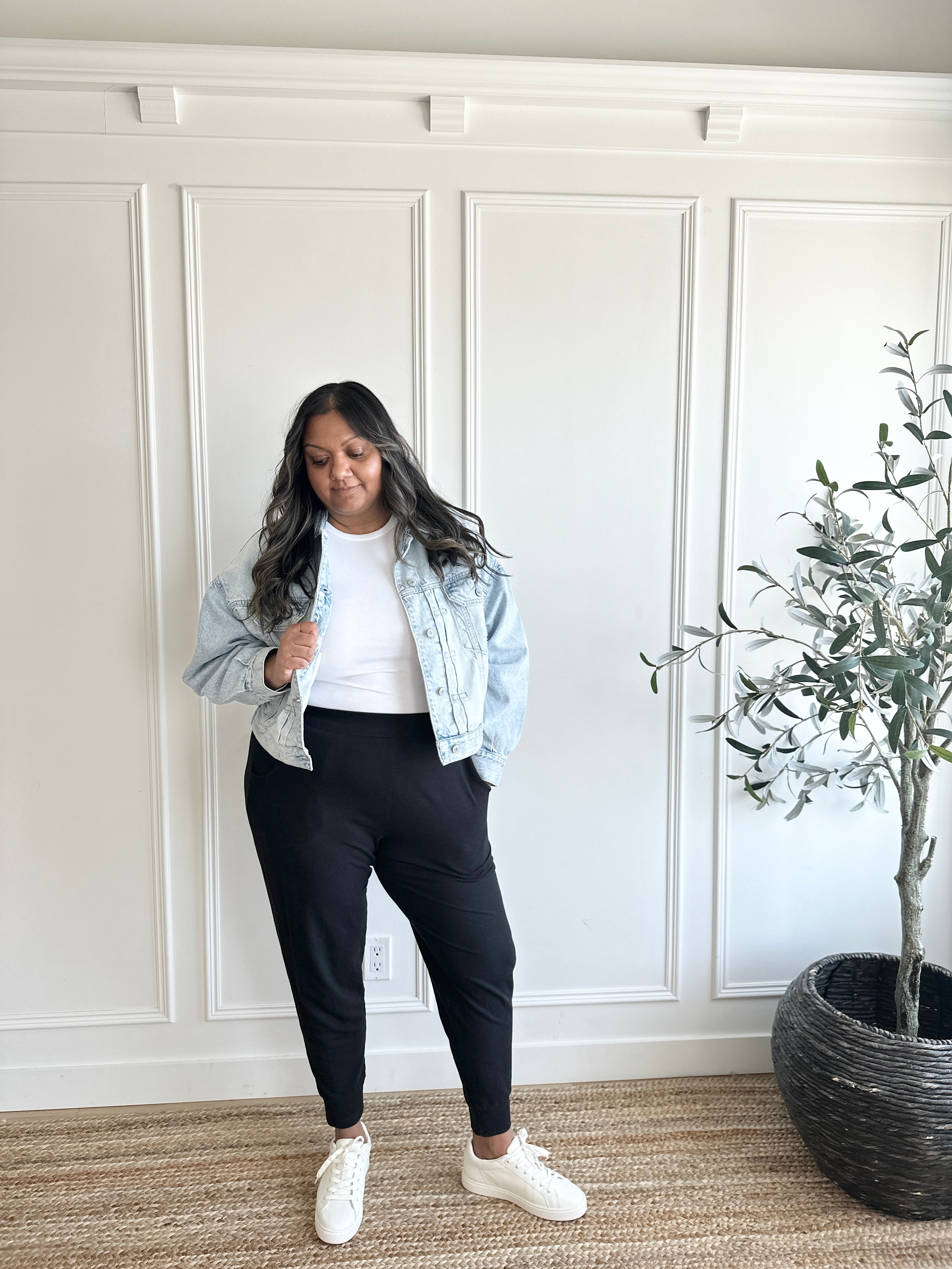 woman wearing jean jacket, white crewneck and black tapered joggers