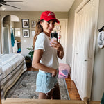 Side view of Model wearing Made in Canada with Love Heart T-shirt Ang Hill with denim shorts and red cap
