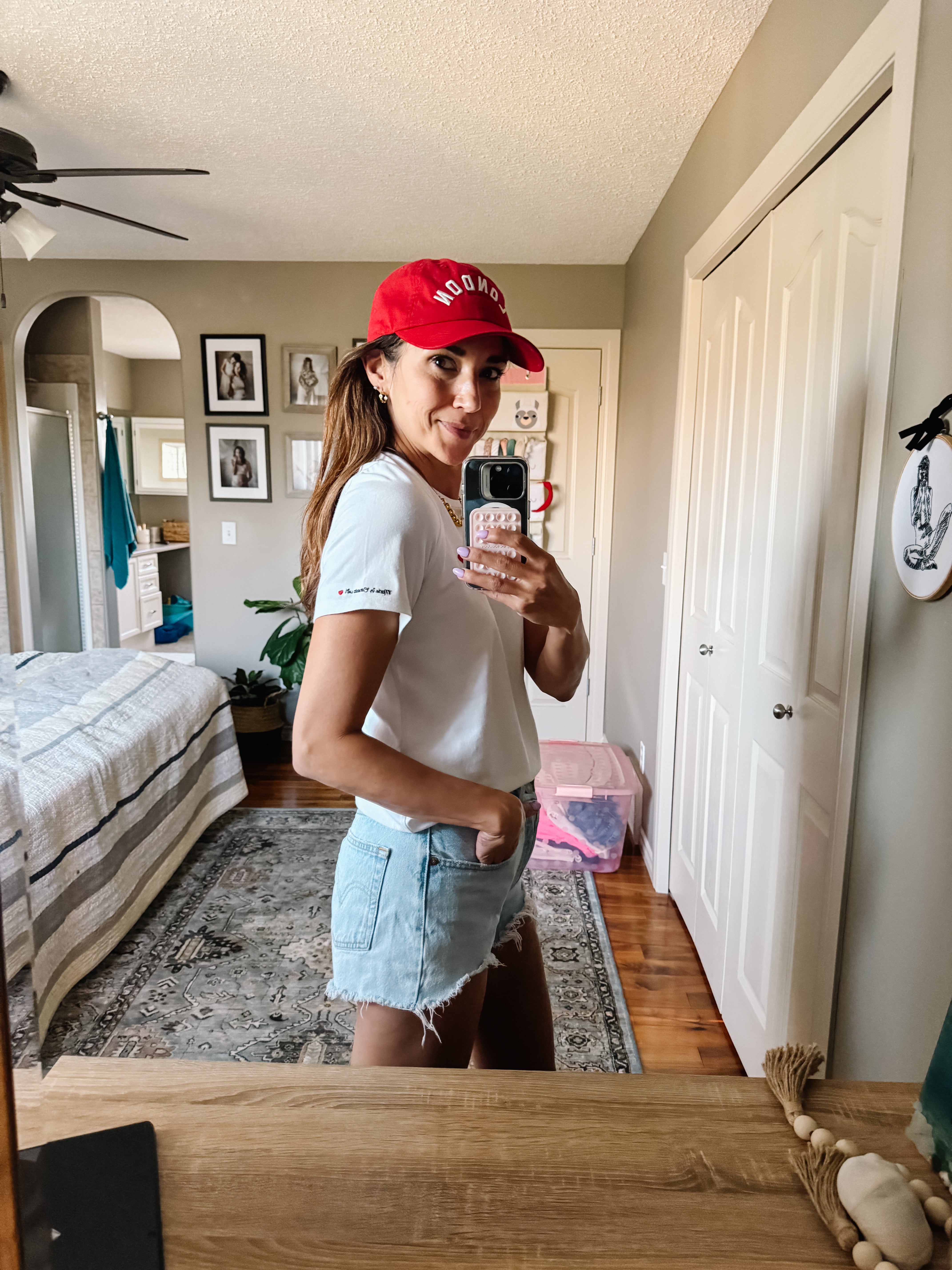 Side view of Model wearing Made in Canada with Love Heart T-shirt Ang Hill with denim shorts and red cap