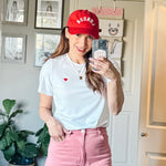 Model wearing Made in Canada with Love Heart T-shirt Ang Hill with pink pants and red cap close up