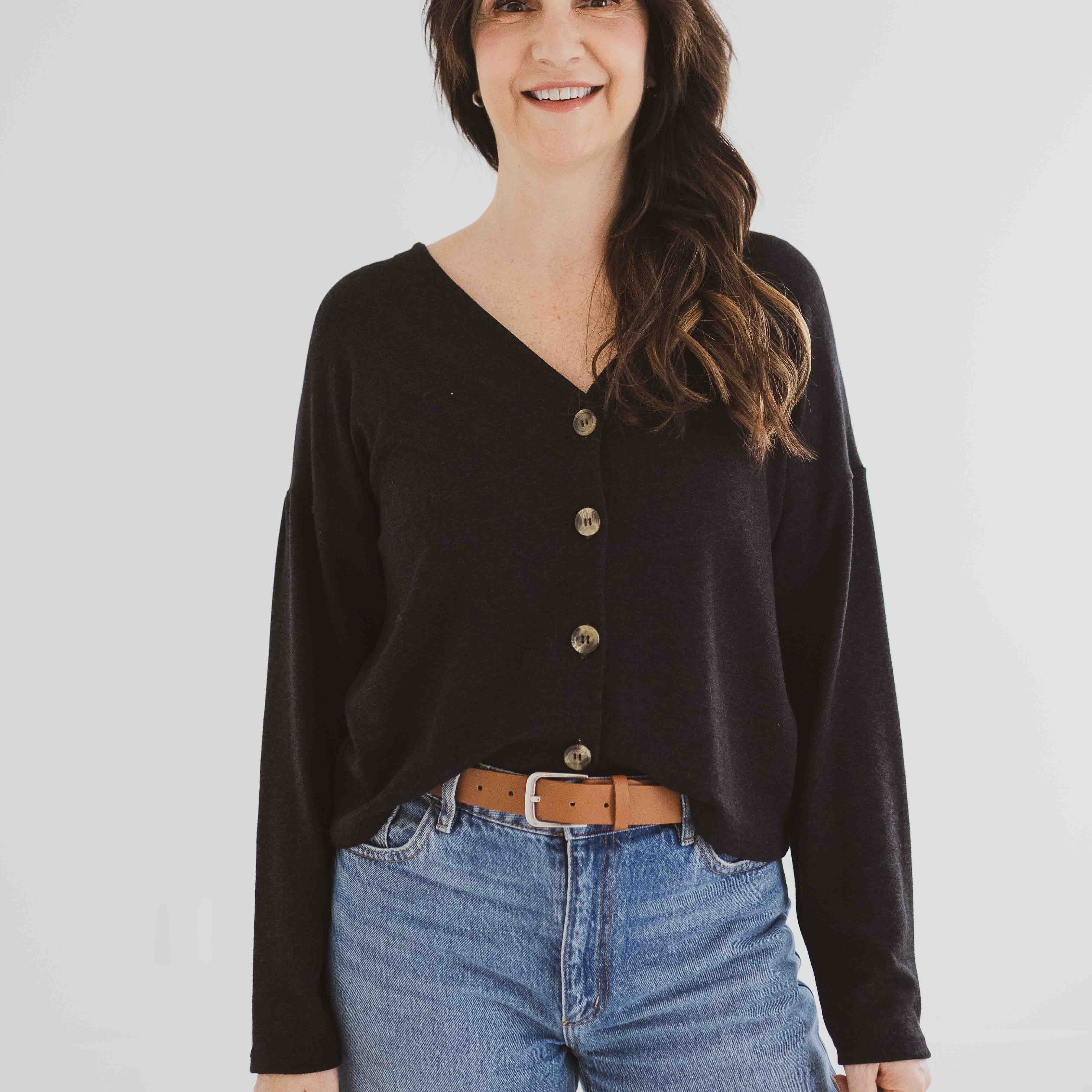 model smiling with holly cardigan with buttons in soft black french tucked into jeans
