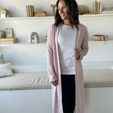 close up of woman wearing long pink cardigan and white high neck tank top