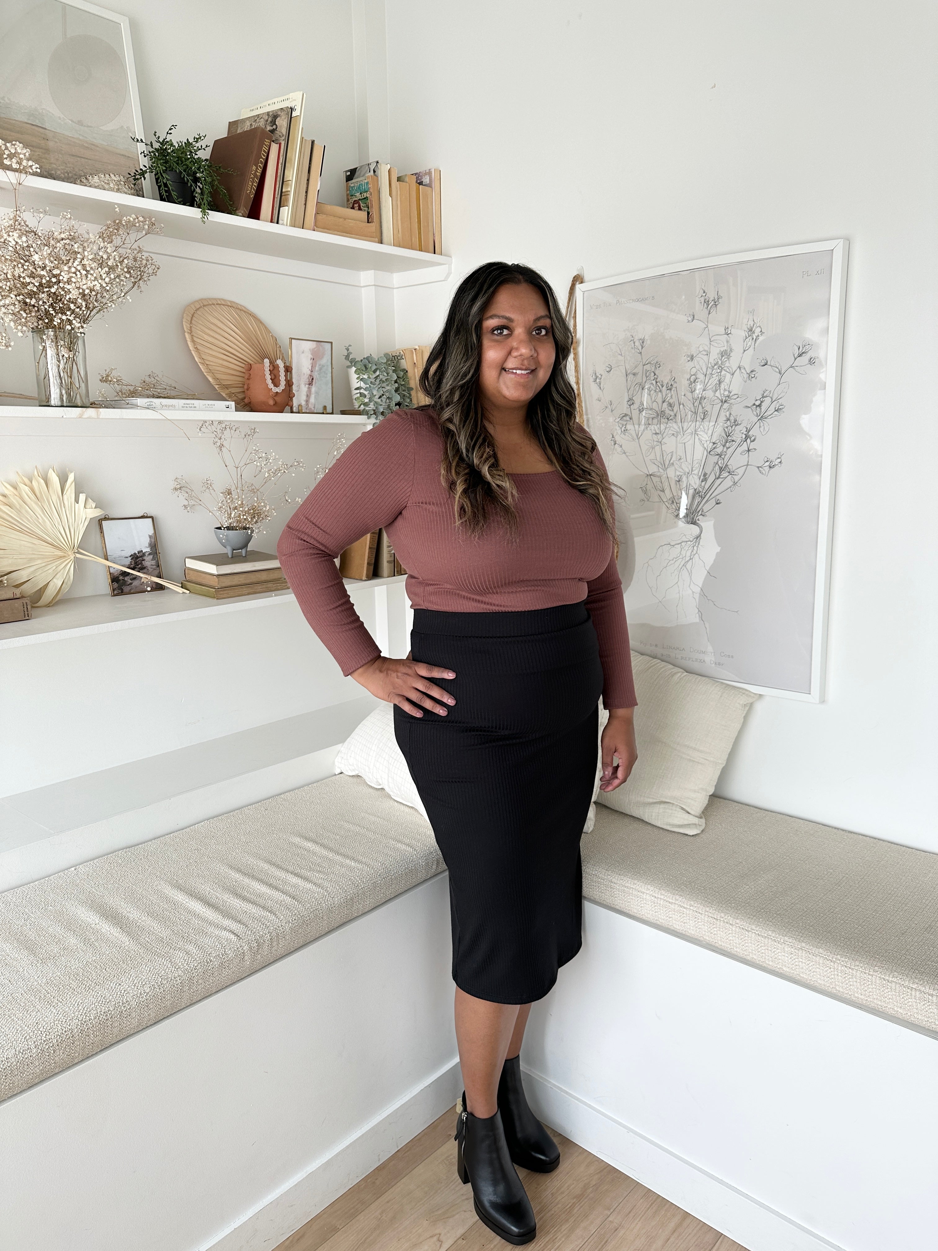 indian woman wearing a long sleeved brown square neck top with black midi skirt and black booties