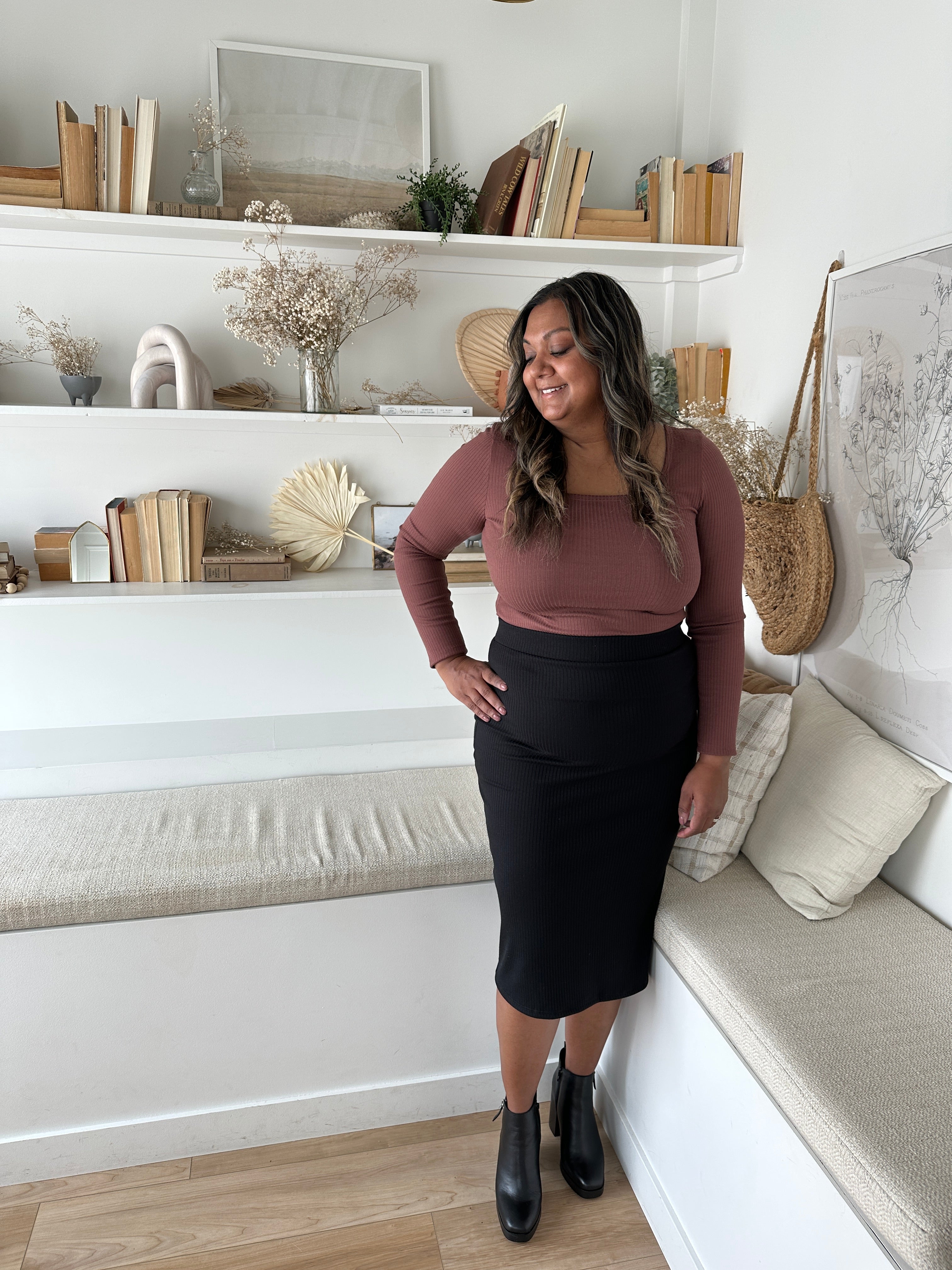 indian woman wearing a long sleeved brown square neck top with black midi skirt and black booties