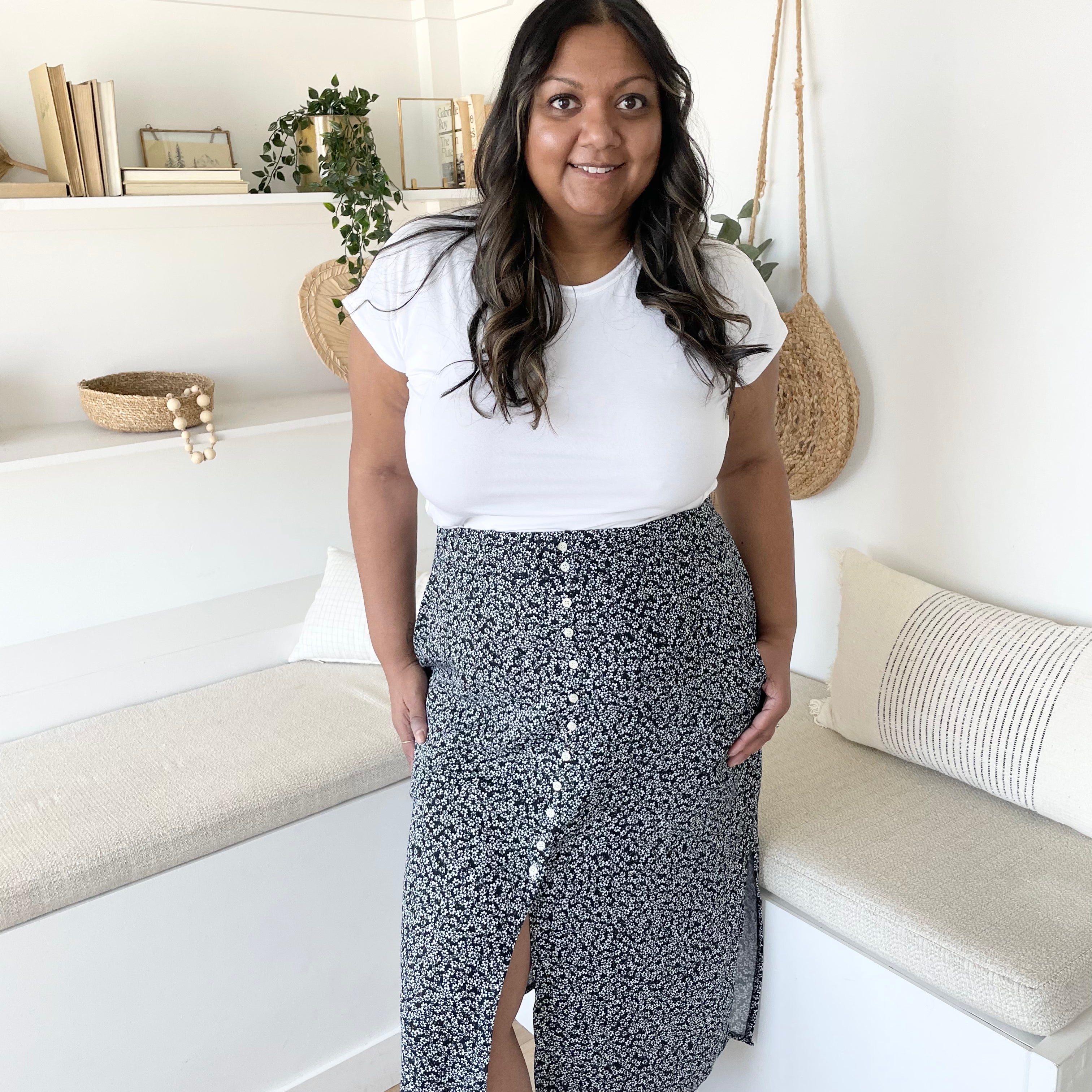 Woman wearing a white top and patterned skirt in a home setting. Apparel made in Canada