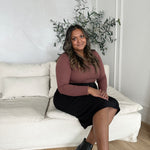 indian woman wearing a long sleeved brown square neck top with black midi skirt and black booties