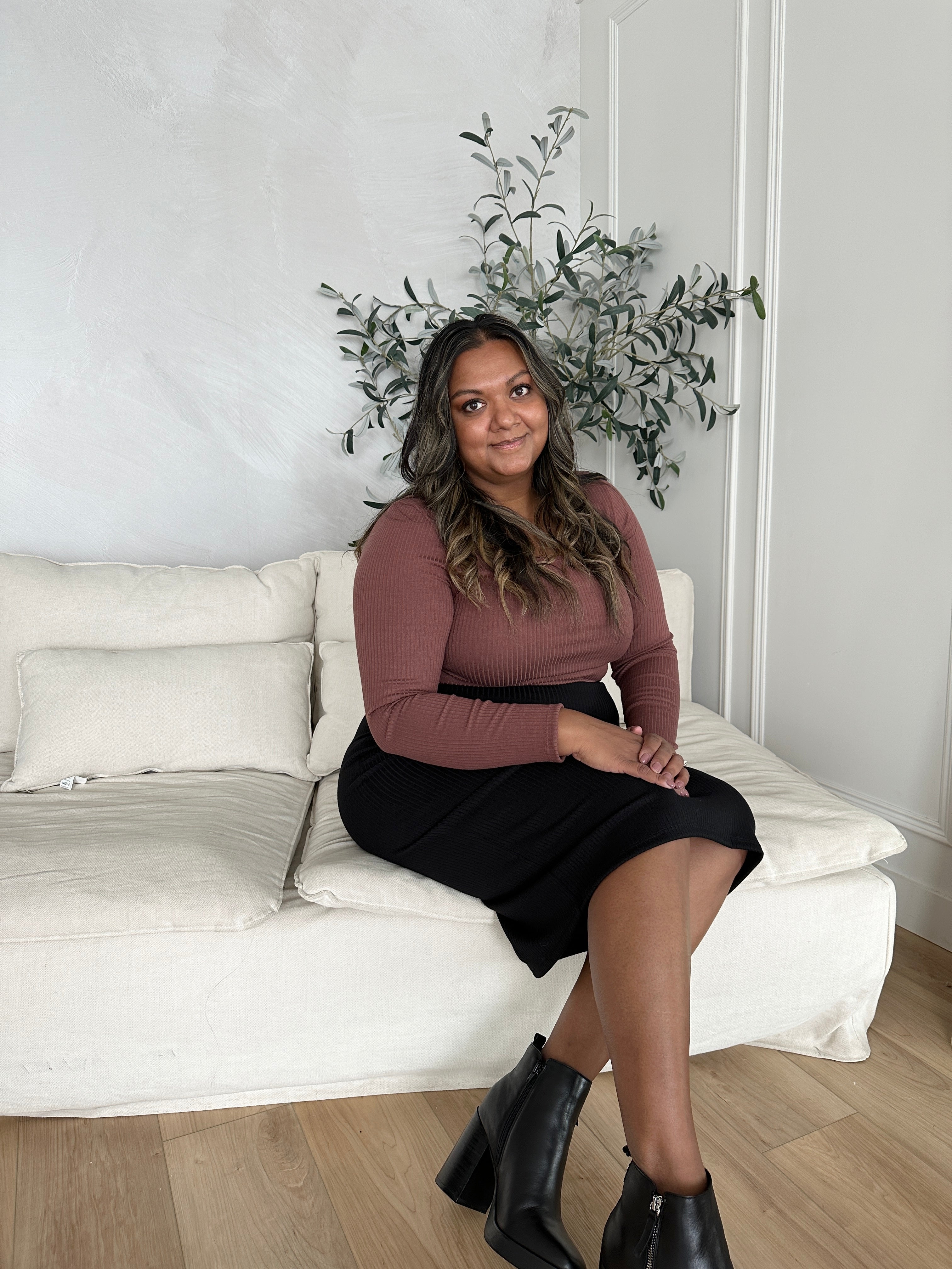 indian woman wearing a long sleeved brown square neck top with black midi skirt and black booties