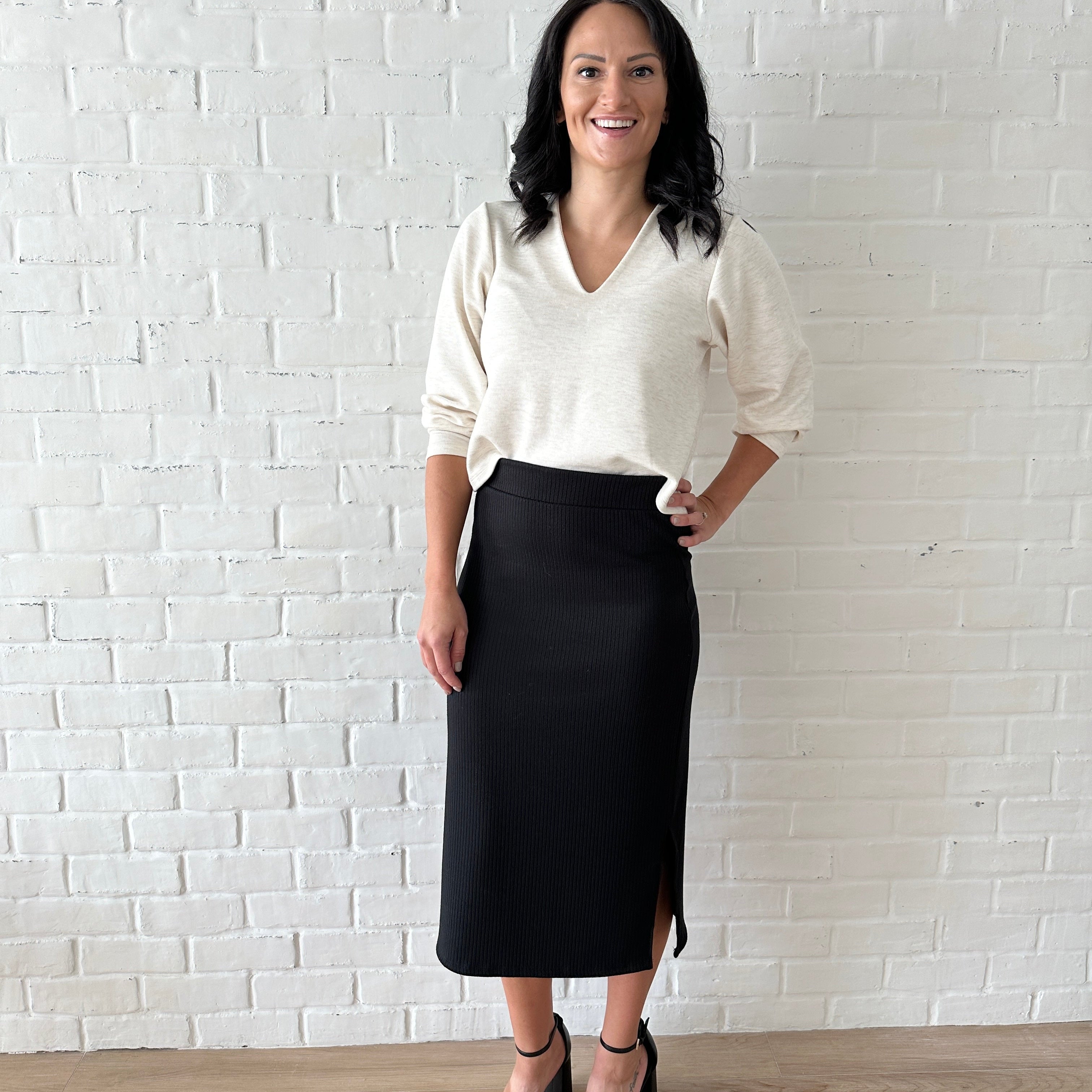 woman wearingcream coloured cropped sweater and black ribbed midi skirt with white sneakers