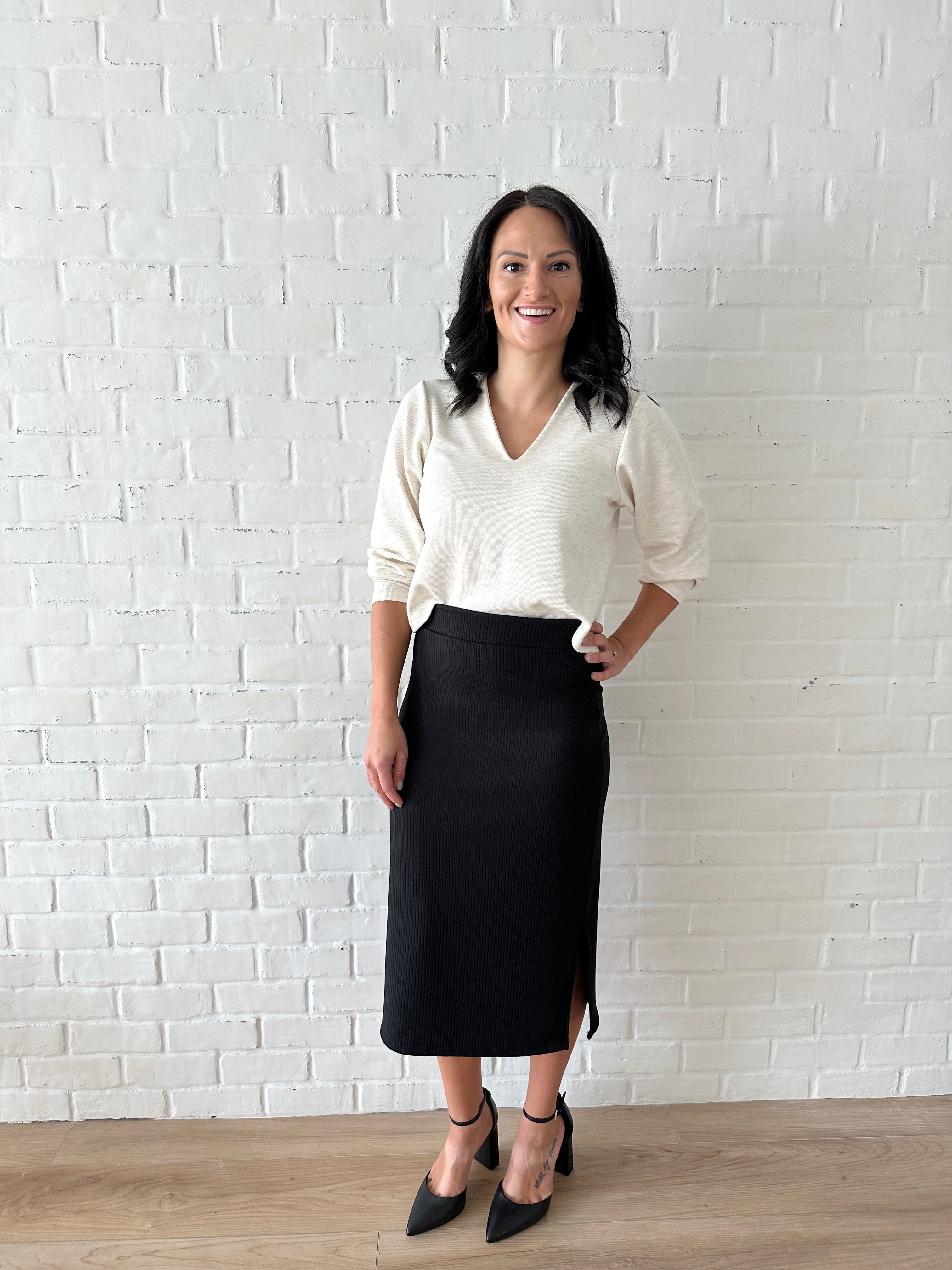 woman wearingcream coloured cropped sweater and black ribbed midi skirt with white sneakers