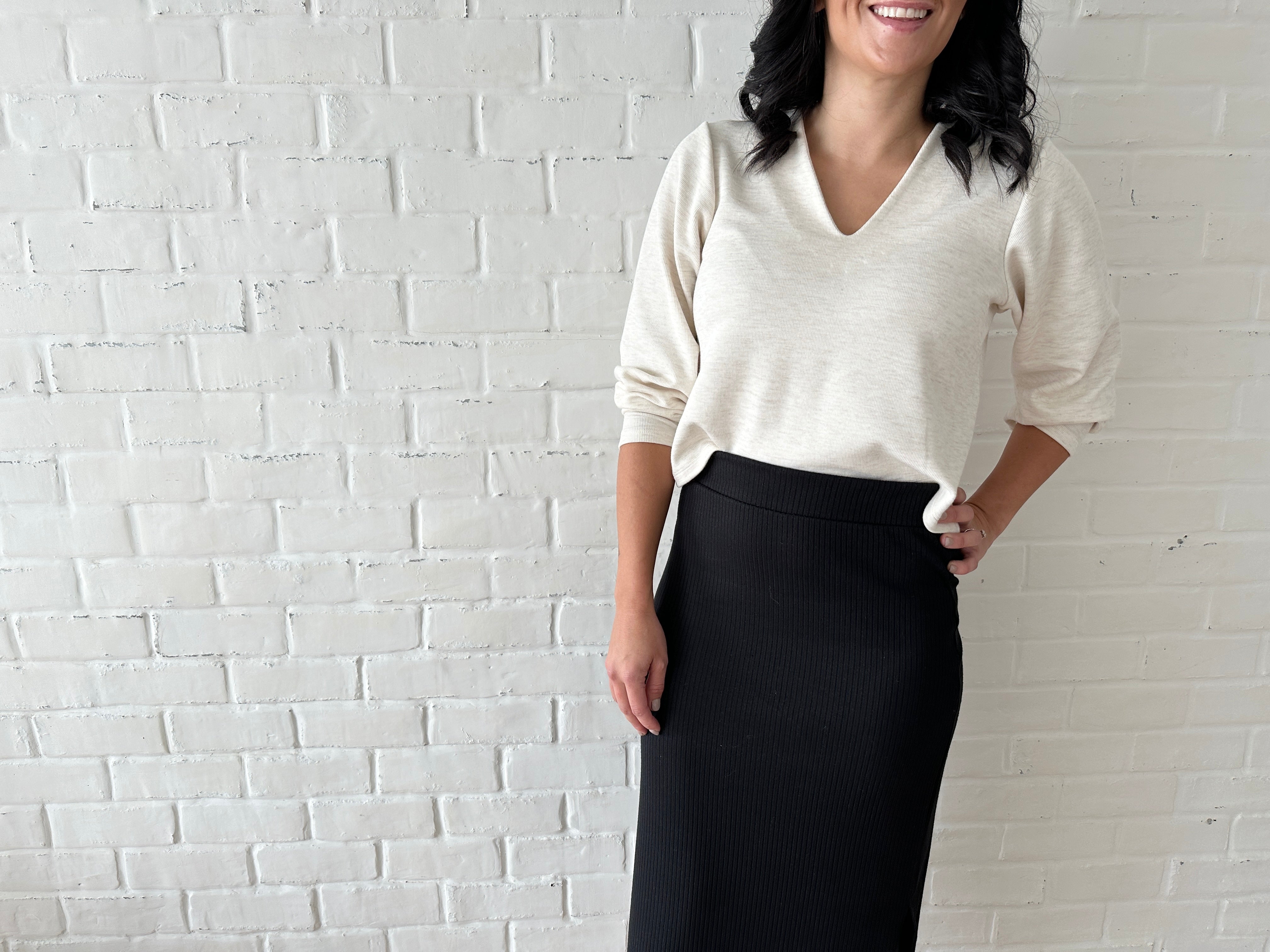 woman wearing cream coloured cropped sweater and black ribbed midi skirt with white sneakers