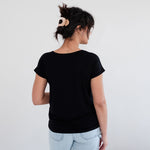Person wearing a black t-shirt and light blue jeans against a white background. Apparel made in Canada