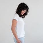 Woman wearing a white t-shirt and light blue jeans against a plain background Apparel made in Canada