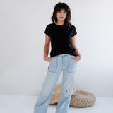 Person wearing a black bamboo t-shirt and light blue jeans standing on a white background. Apparel made in Canada