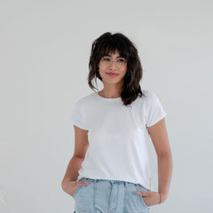 Person wearing a bamboo white t-shirt and light blue jeans against a plain background. Apparel made in Canada