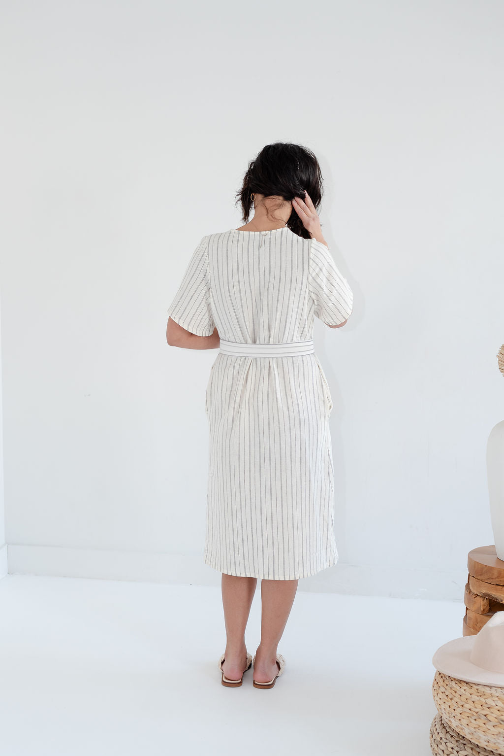 Woman wearing a white dress with vertical stripes against a plain background