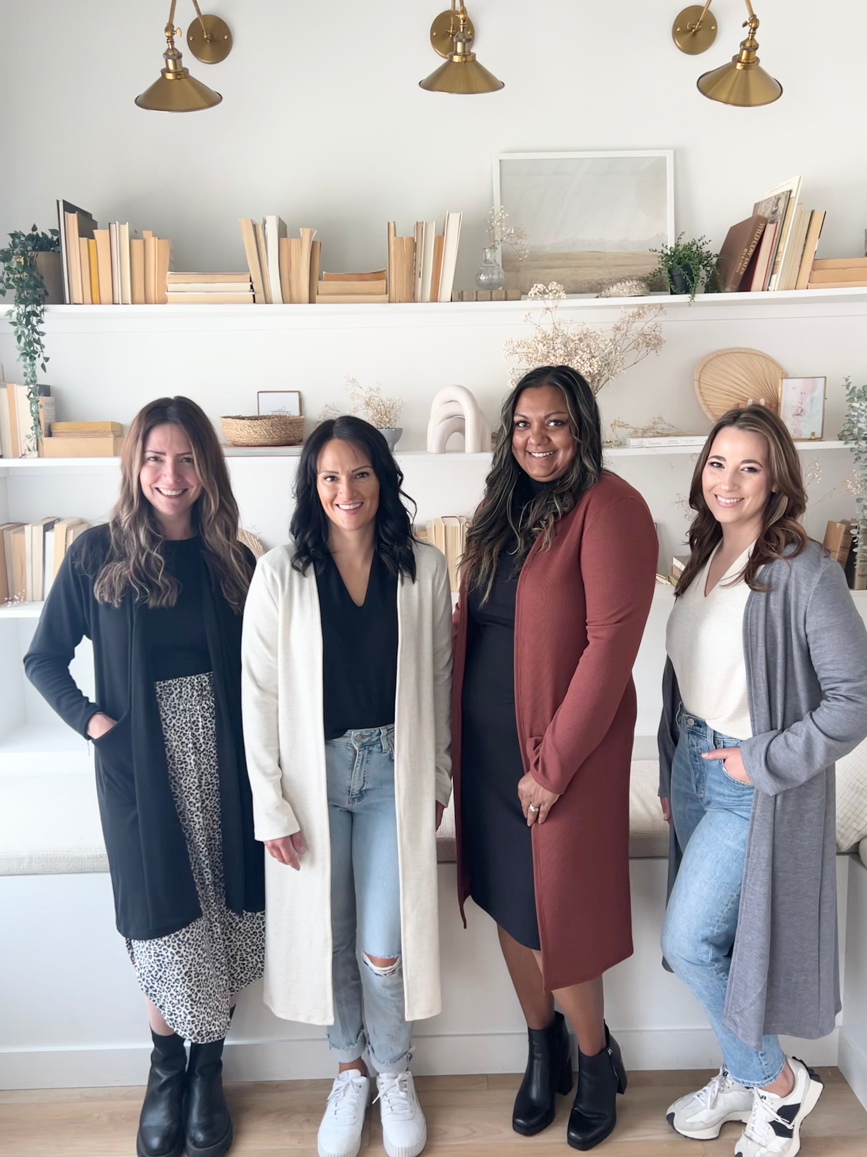 four women wearing long duster cardigan sweaters