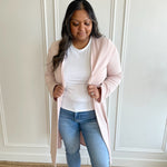 woman wearing a light pink duster long cardigan and a white bamboo t-shirt with light wash jeans