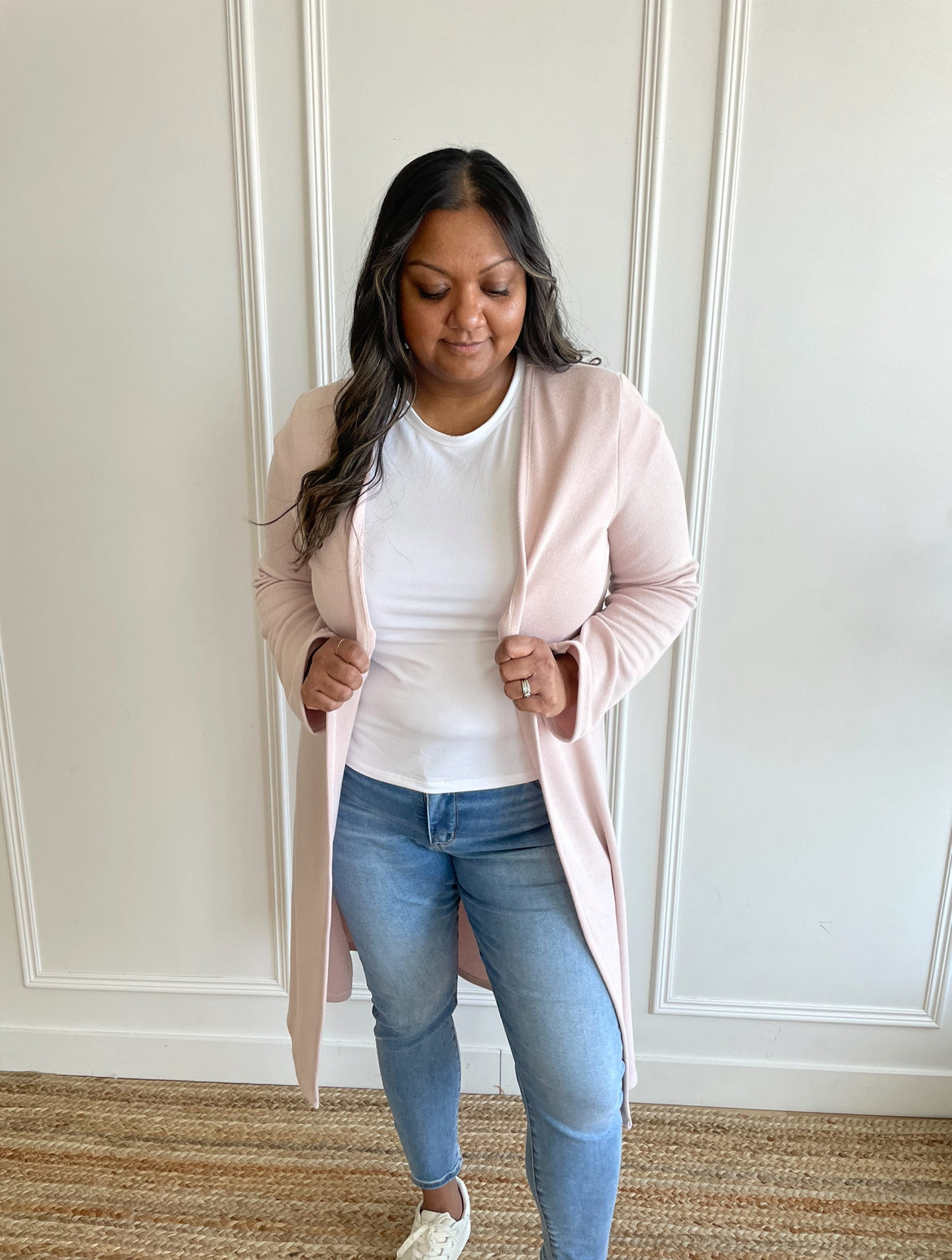 woman wearing a light pink duster long cardigan and a white bamboo t-shirt with light wash jeans