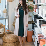 woman wearing long pink cardigan and green high neck tank dress