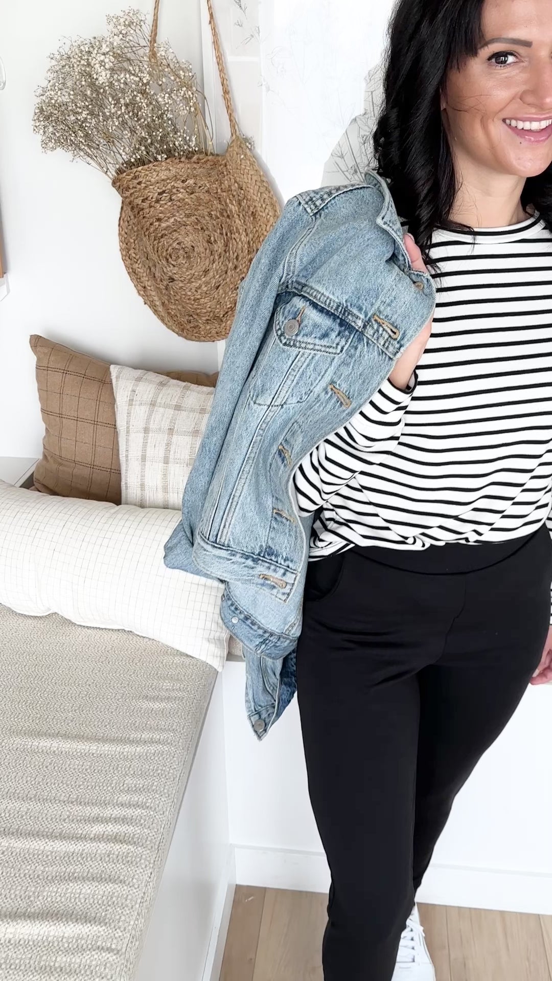 woman wearing black and white bamboo sweatshirt with denim jacket drapped over her shoulder. standing wearing black bamboo tapered joggers with white sneakers